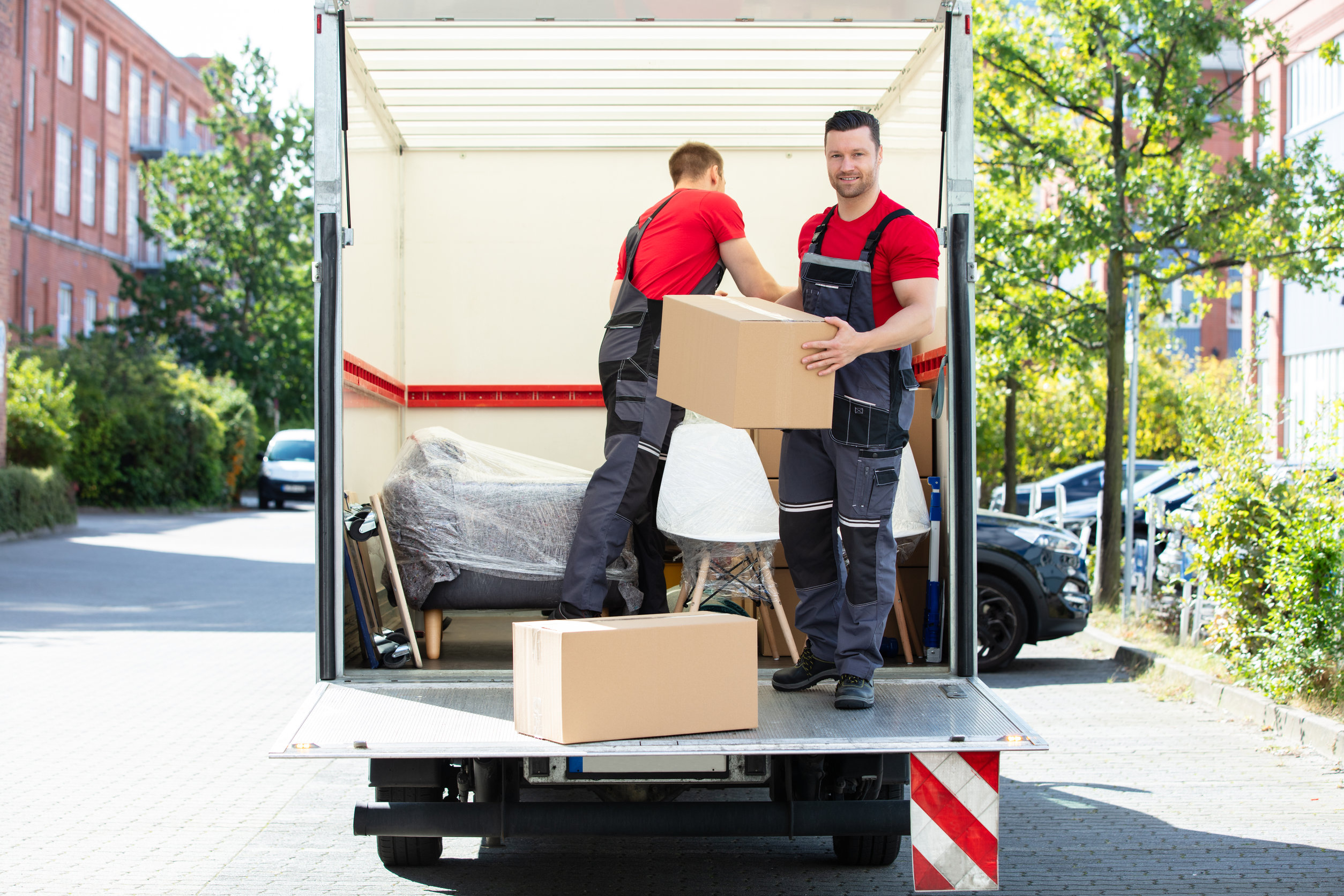 Young Men Stacking The Cardboard Boxes In Moving Truck