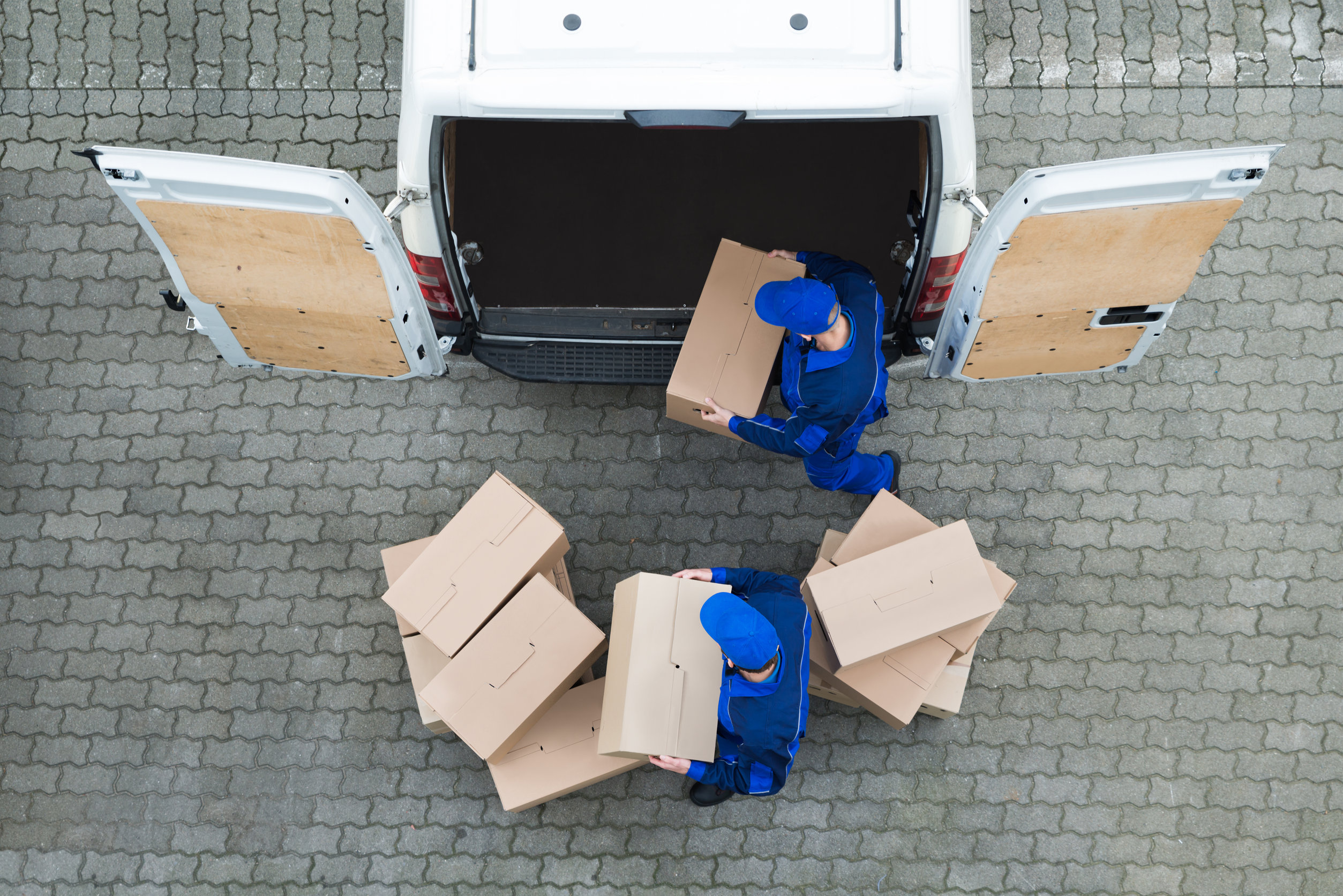 Delivery Men Unloading Cardboard Boxes From Truck On Street